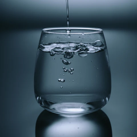 Eau versée dans un verre, sur fond gris bleuté