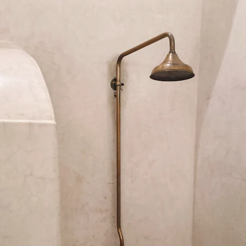 Colonne de douche en laiton sur un mur enduit