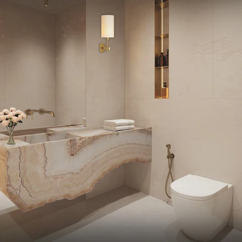 WC à poser blanc, près d'une vasque en onyx et d'une robinetterie laiton