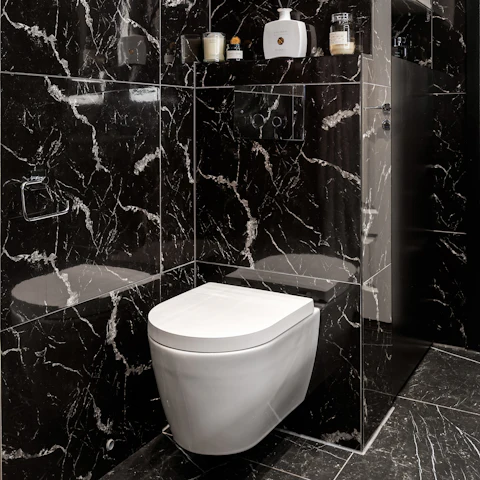 WC suspendu blanc sur un mur noir veiné de blanc
